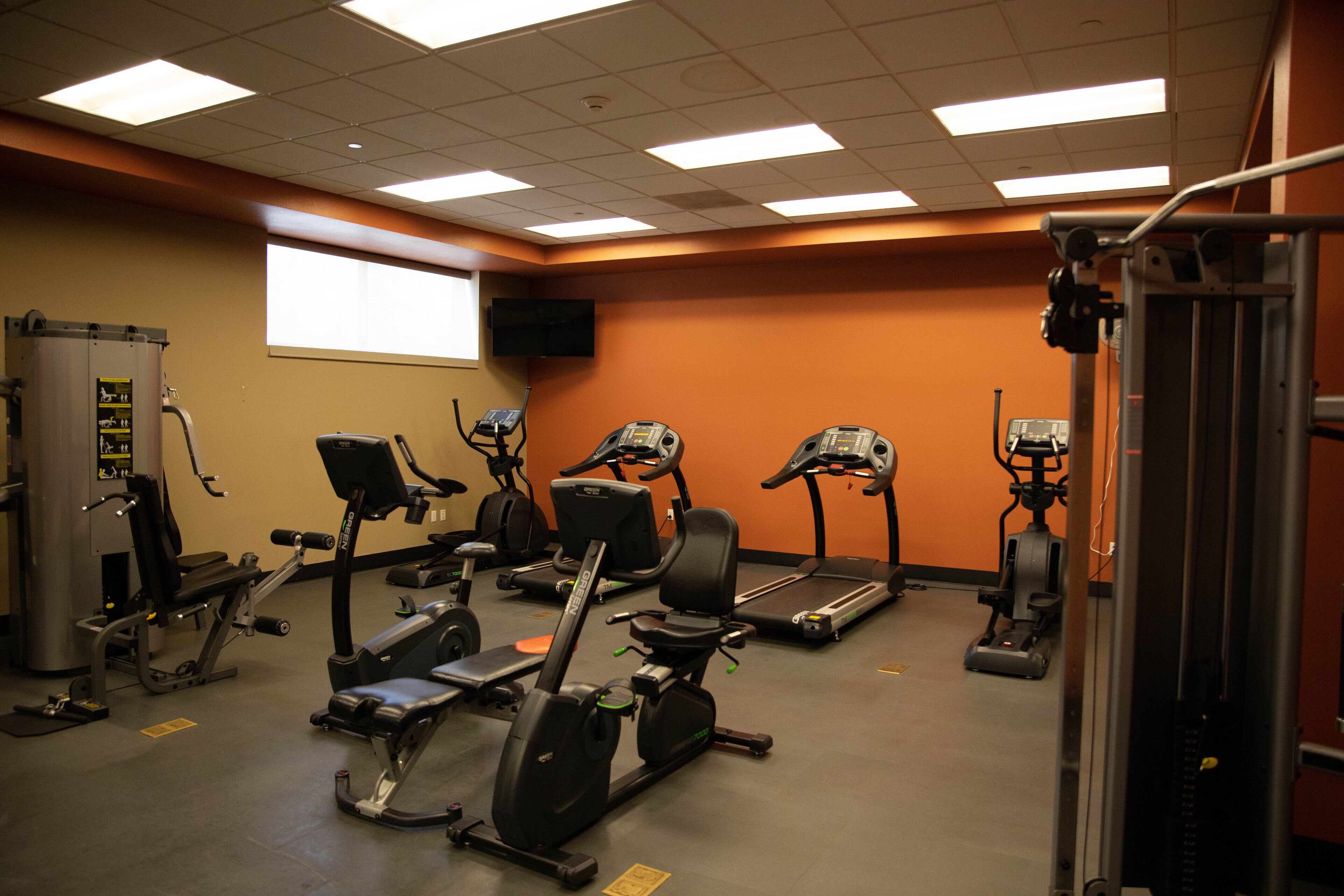 A gym with various exercise equipment, including treadmills, stationary bikes, and weight machines.