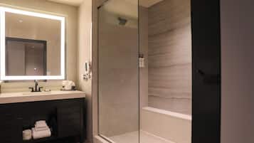 Un bagno moderno con doccia vetrata, uno specchio grande e un mobile lavabo scuro.
