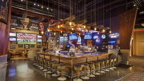 A bar area with multiple screens, stools, and a counter. - The Hotel at Black Oak Casino Resort (Tuolumne)
