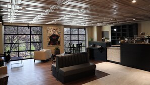 A modern interior with a large window, a sofa, a dining area, and a kitchen counter. - The Hotel at Black Oak Casino Resort (Tuolumne)