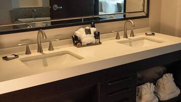 Un baño moderno con lavamanos doble, un espejo grande y un mueble con cajones y un perchero para toallas.