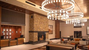 A lobby with a stone fireplace, a reception desk, and a seating area with sofas and a coffee table. - The Hotel at Black Oak Casino Resort (Tuolumne)
