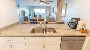 A modern kitchen with a double sink, white cabinets, and a coffee maker. - New,Direct Oceanfront at Amazing Bluewater Resort! (Myrtle Beach)