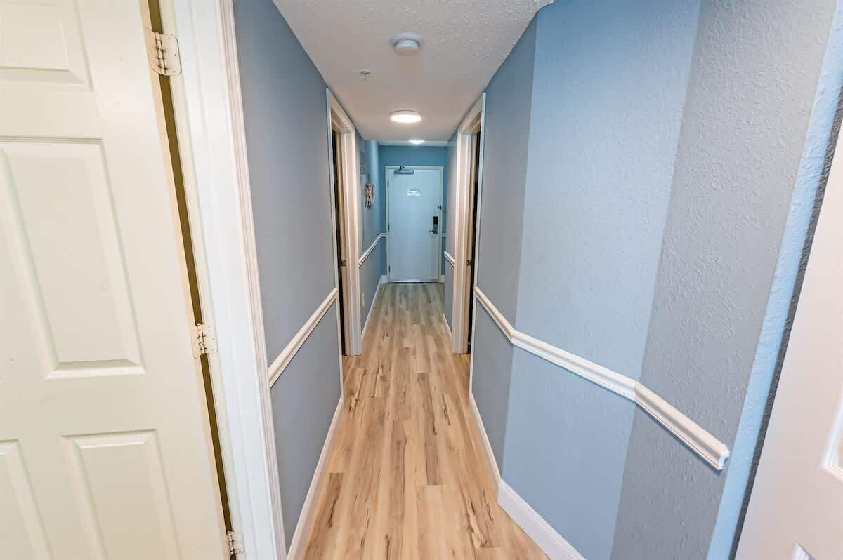 Ein schmaler Korridor mit Holzboden und hellblauen Wänden.