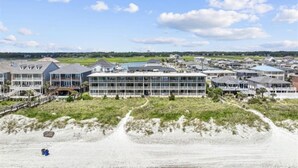 Een kusthotel met meerdere gebouwen, een zandstrand en een heldere lucht.