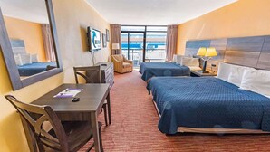 Ein Hotelzimmer mit zwei Betten, einem Schreibtisch, einem Stuhl, einem Fernseher und einem großen Fenster.