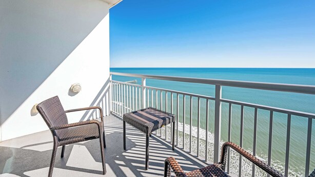 A balcony with wicker furniture and a view of the ocean. - New Direct Oceanfront King 2BR ,Modern Decor,Pools (Myrtle Beach)