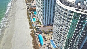 A high-rise hotel with multiple balconies, a pool, and a beachside location. - New Direct Oceanfront King 2BR ,Modern Decor,Pools (Myrtle Beach)