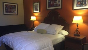 Una habitación de hotel con una cama grande, dos lámparas de noche y cuadros en las paredes.