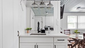 A modern kitchen with white cabinetry, a central island, and a dining area with wooden chairs.