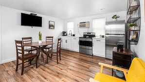 Una cocina moderna con armarios blancos, un refrigerador de acero inoxidable y un horno empotrado.
