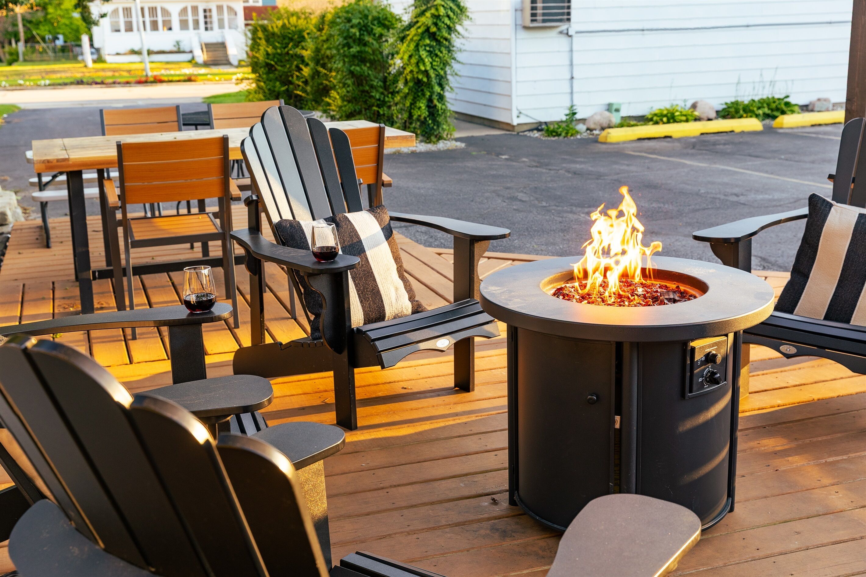 A deck with Adirondack chairs, a round table, and a fire pit.