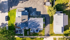 Une vue aérienne d’un bâtiment avec un parking, de nombreux autres bâtiments et un espace verdoyant où flotte un drapeau.