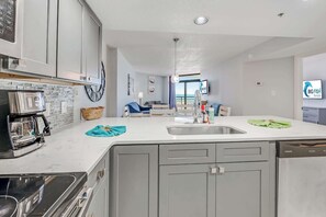 A modern kitchen with a central island, stainless steel appliances, and a view to the outside. - Amazing North Tower at Sand Dunes Resort (Myrtle Beach)