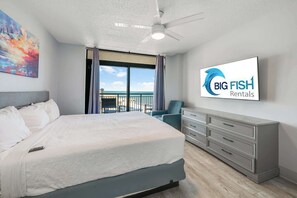 Een slaapkamer met een bed, een plafondventilator, een televisie, een dressoir en een balkon met uitzicht.