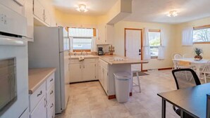 A modern kitchen with white cabinets, a central island, and a dining area with a table and chairs.