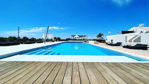 Piscina com espreguiçadeiras e deck de madeira.