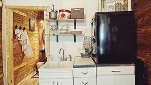Una cucina compatta con mobili bianchi, un frigorifero nero e un soffitto in legno.