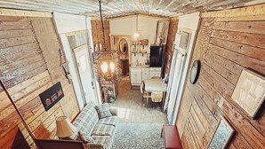 Una camera mansardata accogliente con pavimento in legno, un divano a scacchi, un tavolo da pranzo e una scala che scende.