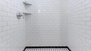 A bathroom with white subway tiles, a black and white checkered floor, and a chrome shower head.