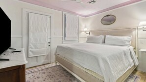 A bedroom with a bed, a ceiling fan, a mirror, and a nightstand.
