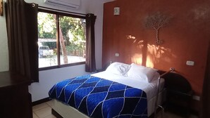 A bedroom with a bed, a window, and a wall-mounted air conditioner.