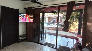 A room with a sliding glass door leading to an outdoor area with a pool and lounge chairs.