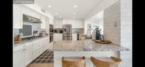 A modern kitchen with white cabinetry, stainless steel appliances, and a granite countertop.