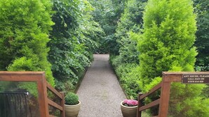 A wooden deck leading to a gravel path surrounded by lush greenery. - Relaxing couples getaway with hot tub (Congleton)
