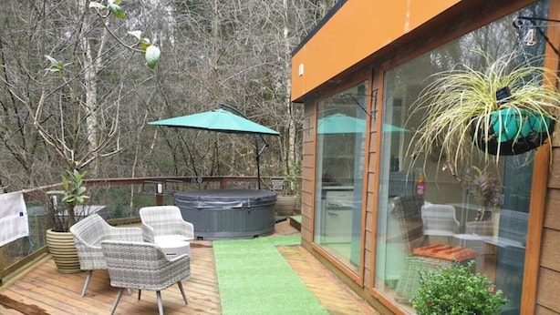 A deck with outdoor furniture, a hot tub, and a glass-enclosed room with a potted plant. - Relaxing couples getaway with hot tub (Congleton)