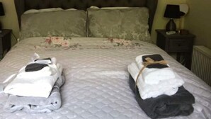 A neatly made bed with a quilted cover, two pillows, and two folded towels on the bed. - Relaxing couples getaway with hot tub (Congleton)