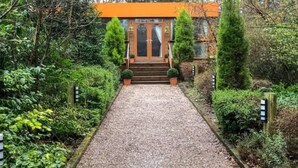 A pathway leading to a building with a wooden door and a sign above it. - Relaxing couples getaway with hot tub (Congleton)