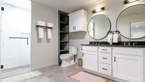 Un baño moderno con ducha, inodoro y tocador con dos espejos.