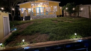 A two-story house with a porch, a small deck, and a covered area with string lights.