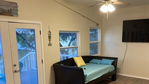 A bedroom with a bed, a ceiling fan, and a TV mounted on the wall.