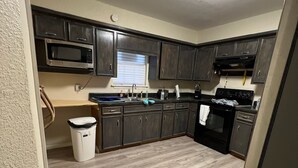 A kitchen with dark cabinets, a microwave, a sink, and a stove.