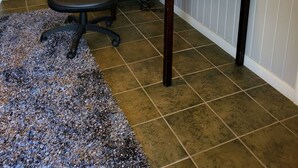 Una habitación con un escritorio de madera oscura, dos lámparas, una silla y un espejo en la pared.