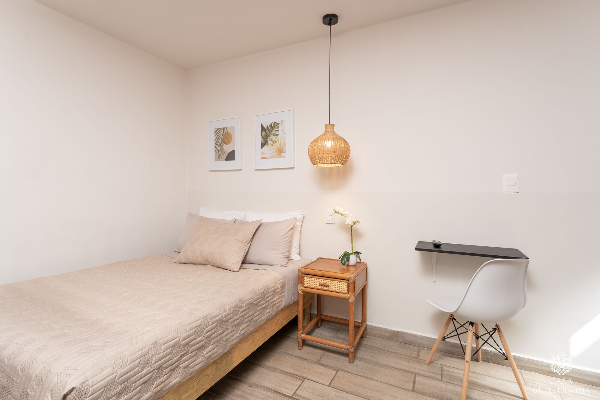A bedroom with a bed, a bedside table with a lamp, a chair, and a shelf.