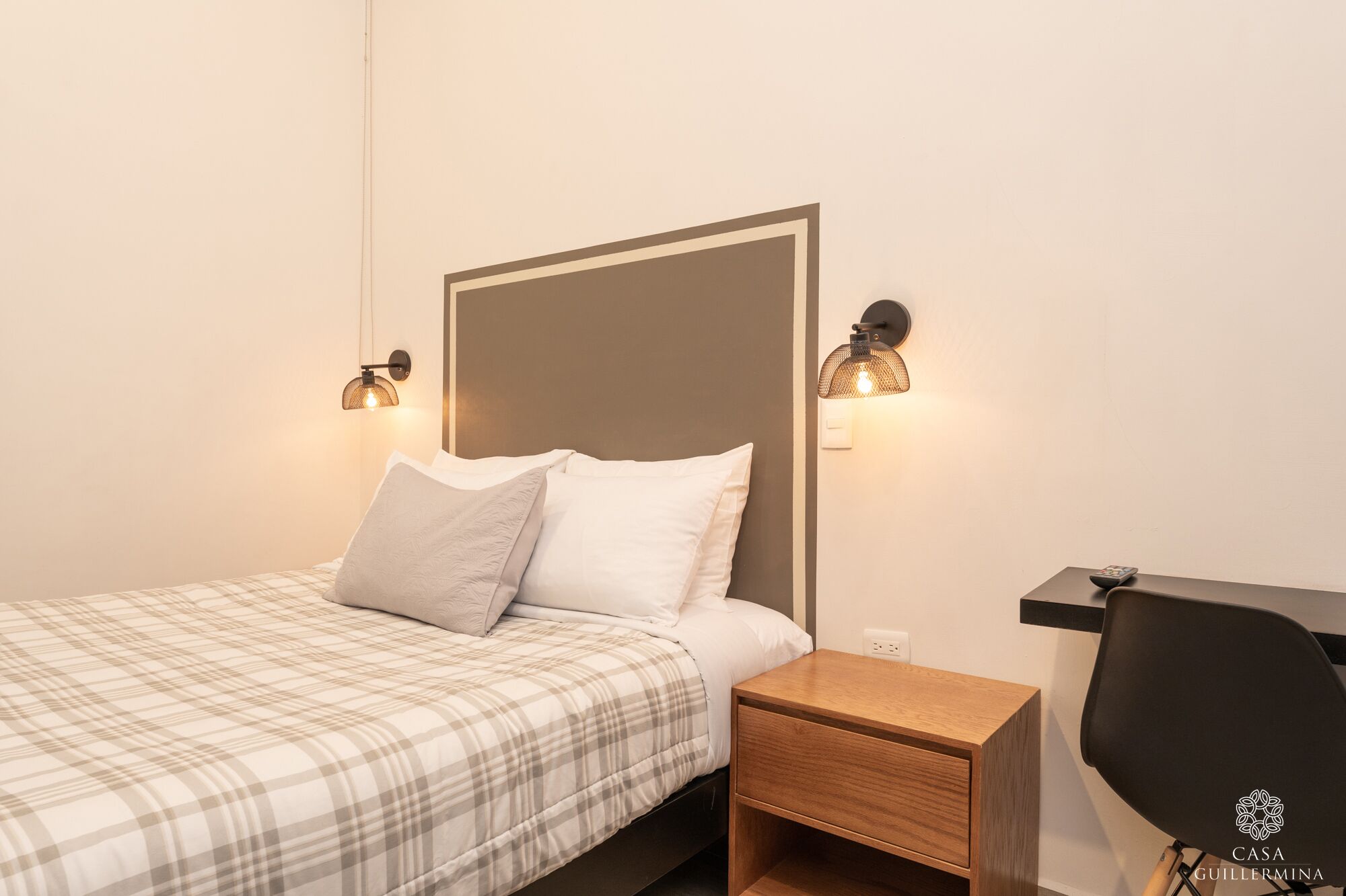 Un dormitorio con cama, mesitas de noche y lámparas de pared.