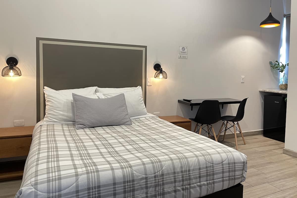 A modern bedroom with a bed, two bedside lamps, a desk, and a chair.