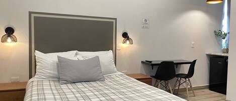 A modern bedroom with a bed, two bedside lamps, a desk, and a chair.