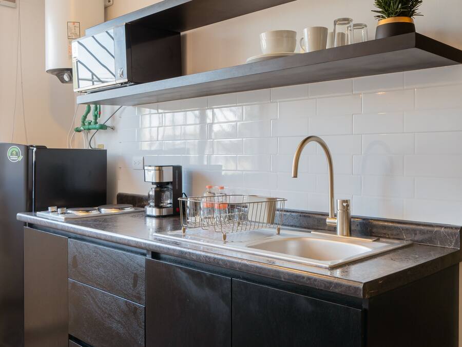 Una cocina moderna con una isla integrada, electrodomésticos de acero inoxidable y un suelo con estampado blanco y negro.