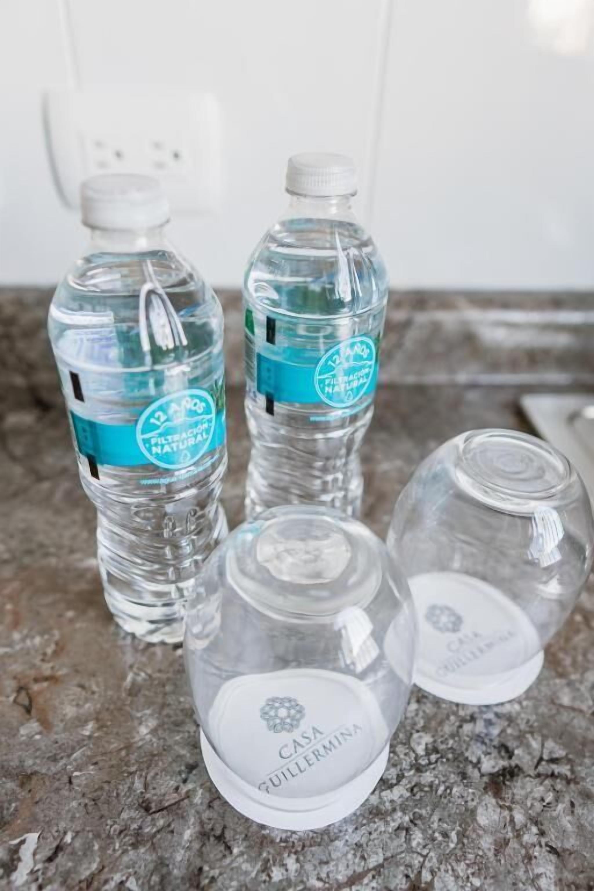 Quatre bouteilles d’eau et deux bocaux en verre sur un comptoir en granit.