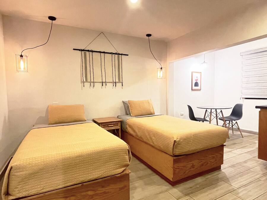 A small, modern room with two single beds, a desk, and a chair.