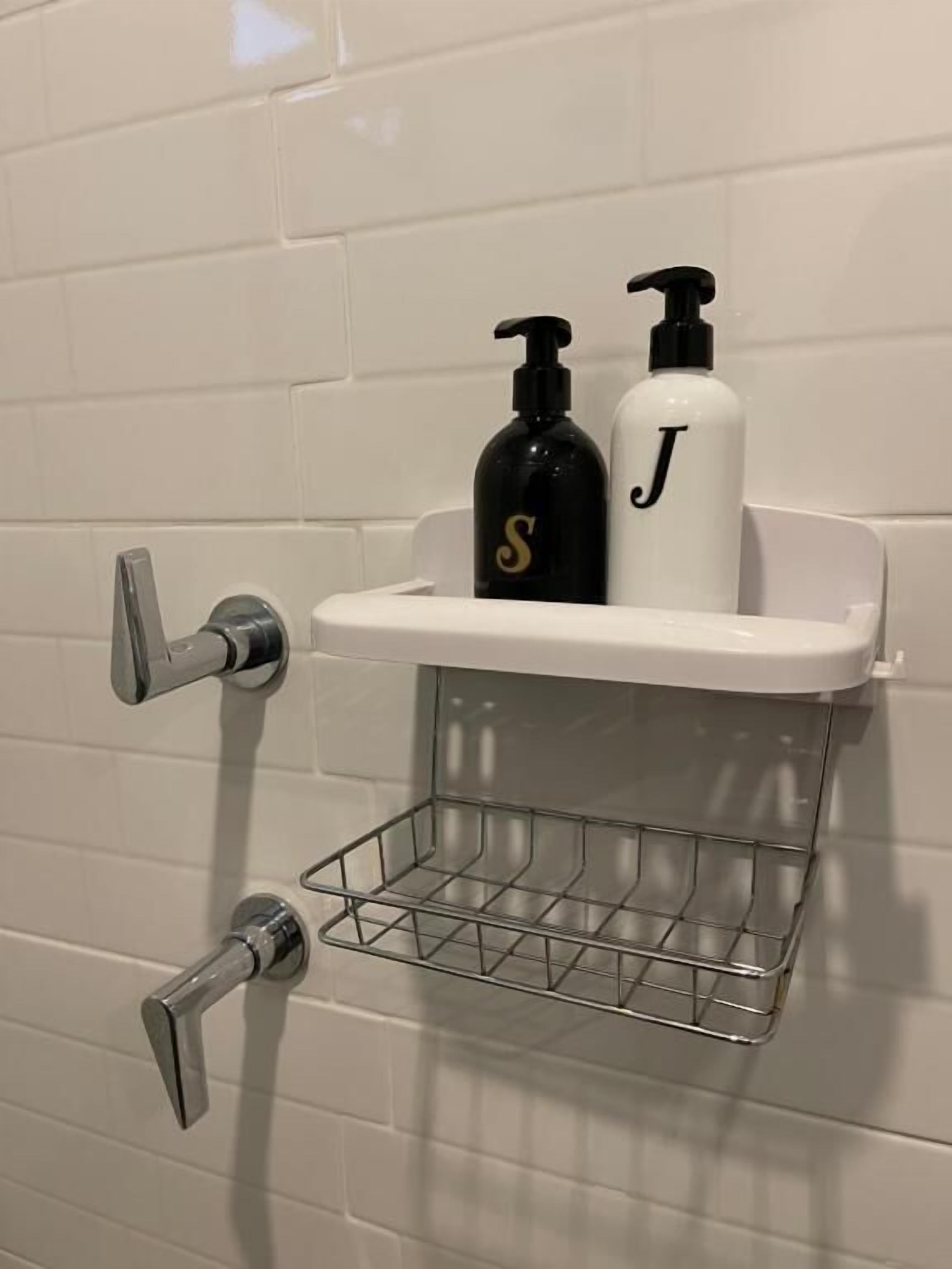 A bathroom with a white tiled wall, a chrome faucet, and a shelf holding two bottles with pumps.