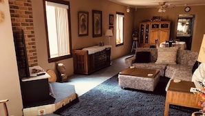Un salon avec une cheminée, un ventilateur de plafond et une grande fenêtre.