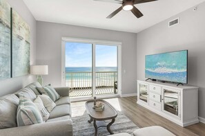 Relax in this stylish living room with a sofa, coffee table, and flat-screen TV, offering a view of the beach.