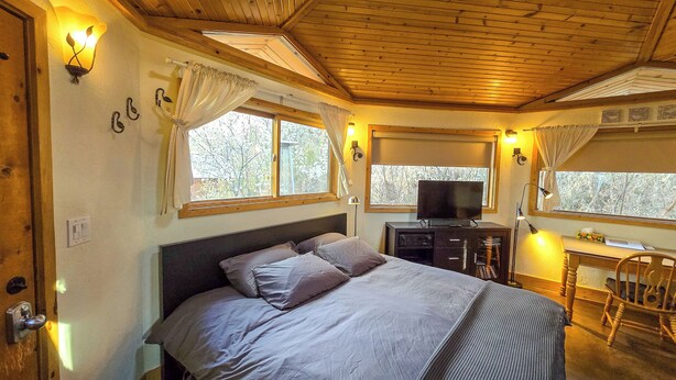 Un dormitorio con cama, televisor, escritorio y silla.