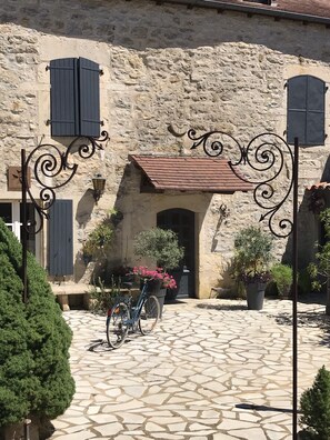 A stone building with a tiled entrance, potted plants, and a bicycle.