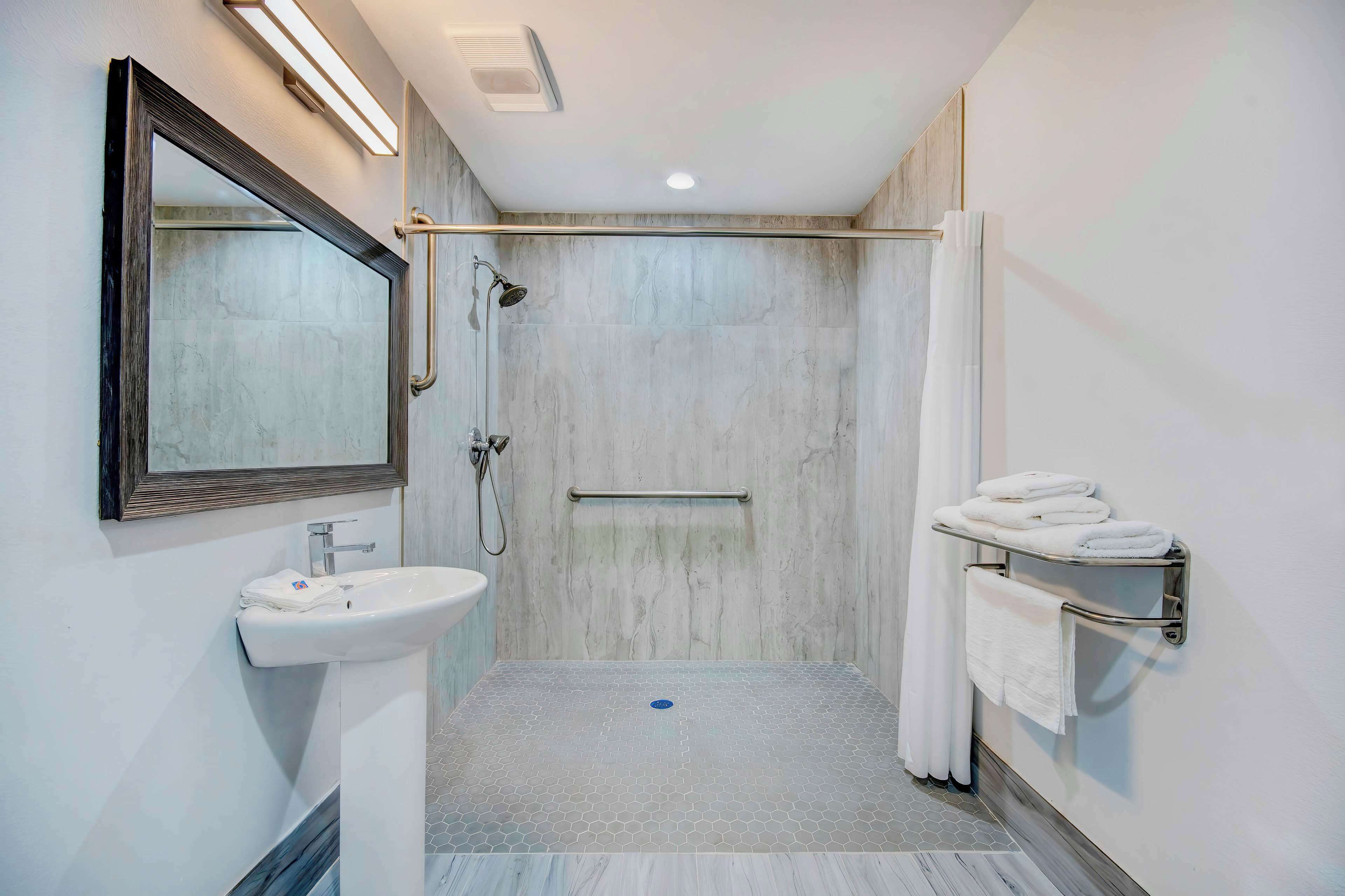 Une salle de bain moderne équipée d’une douche, d’un lavabo et d’un porte-serviettes.